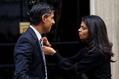 Akshata Murty, the wife of  Rishi Sunak, pins a poppy on the British Prime Minister on Monday. Barely a week into his premiership, Mr Sunak is facing difficulties after his Home Secretary Suella Braverman referred to a migrant 'invasion' of Britain. Reuters
