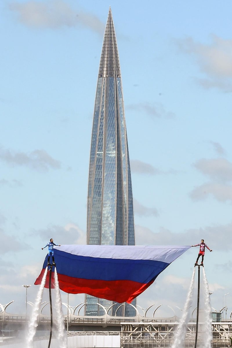 Members of the Russian hydroflight team hold the Russian national flag during the Russia Day celebration in front of the 462 meter Lakhta Center's tower in St. Petersburg's Lake Lakhta on June 12, 2020. - President Vladimir Putin on on June 12, 2020 was set to make his first public appearance after weeks of lockdown as Russia reported nearly 9,000 new coronavirus cases in one day. Russia, the country with the world's third-largest coronavirus outbreak, this week lifted tight lockdown restrictions as Putin sets the stage for a vote on July 1 that could extend his hold on power until 2036. (Photo by OLGA MALTSEVA / AFP)