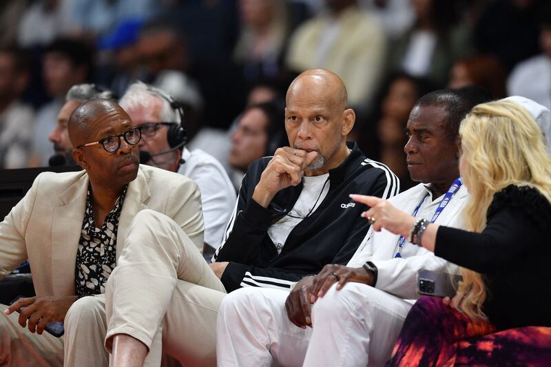 American sports commentator and former basketball player Kenny Smith, left, and American former basketball player Kareem Abdul-Jabbar, centre, sit courtside. AFP