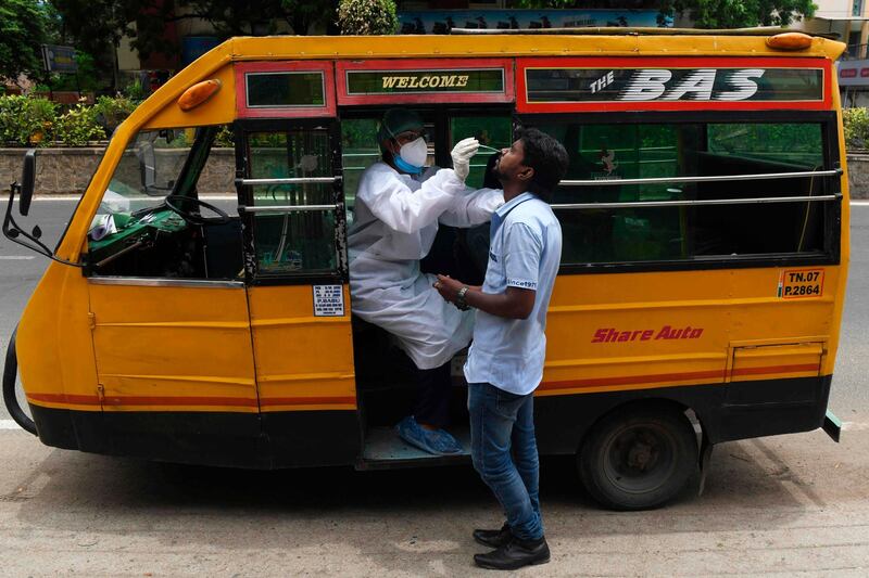 A health worker wearing Personal Protective Equipments (PPE) suit, sits in a share auto-rickshaw as she collects a swab sample from a man to test for the Covid-19 coronavirus, outside a commercial centre in Chennai.  AFP