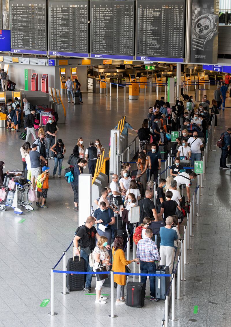 Passengers wearing face masks wait in the outbound queue at Frankfurt airport, in Germany.