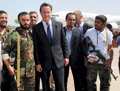 British Prime Minister David Cameron (C) poses with Libyan rebels upon his arrival at Benghazi Airport on September 15, 2011, during a one-day visit to Libya with French President Nicolas Sarkozy (unseen). Cameron and Sarkozy, whose countries spearheaded the NATO air campaign against Kadhafi, arrived in Tripoli earlier in the day as the first major Western leaders to visit the country since the capital was seized on August 23. AFP PHOTO / POOL / Stefan Rousseau (Photo by STEFAN ROUSSEAU / POOL / AFP)
