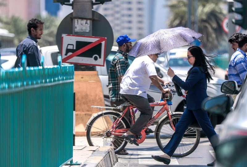 Abu Dhabi, United Arab Emirates, July 15, 2019.  Standalone weather images.  Pedestrians protect themselves with umbrellas while crossing a street at downtown Abu Dhabi.
Victor Besa/The National
Section:  NA
Reporter: