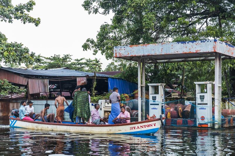 People sitting on a boat sail past Indian Oil Corp. diesel fuel pumps submerged in floodwater in Kainakary village in the district of Alappuzha, Kerala, India, on Wednesday, Aug. 22, 2018. India's tourist hub of Kerala is shifting its focus to relief and rehabilitation work to assist millions of people affected by the worst flood in a century as rescue operations wind down. Photographer: Prashanth Vishwanathan/Bloomberg