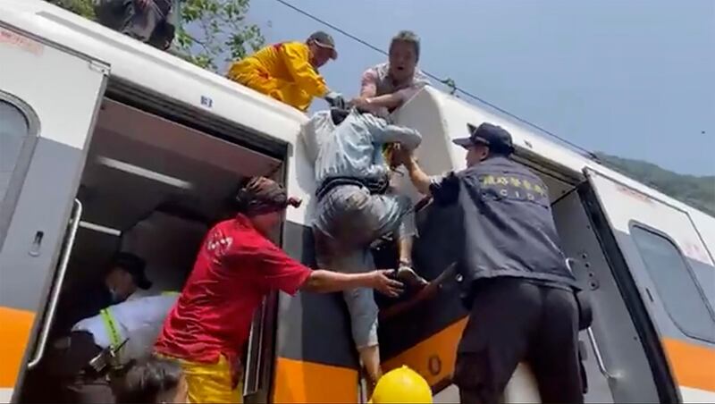 In this image made from a video released by hsnews.com.tw, a passenger is helped to climb out of a derailed train in Hualien County in eastern Taiwan.  AP