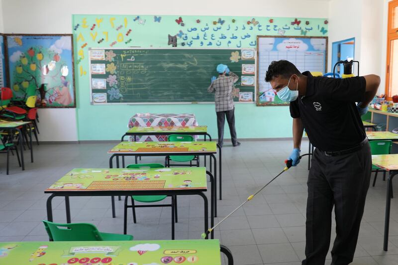 A Palestinian worker wearing a protective face mask cleans a classroom in a UN-run school before the start of a new academic year in Gaza City. Reuters