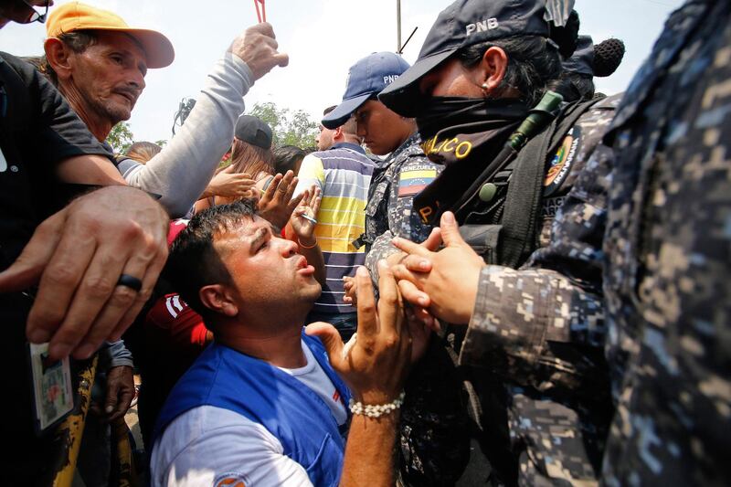 A supporter of Venezuela's opposition leader Juan Guaido kneels in front of members of Venezuela's National Police standing guard at the Francisco de Paula Santander International Bridge between Colombia and Venezuela. AFP