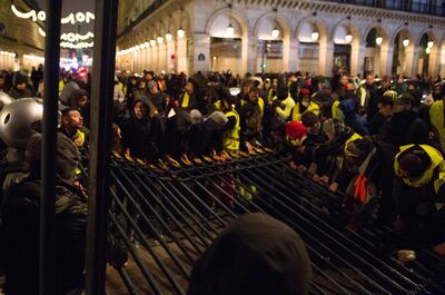 TOPSHOT - Protestors wearing a yellow vest (Gilets jaunes) pull down the grating of the Tuileries Gardens next to the rue de Rivoli, in central Paris, during a demonstration against the rising oil prices and living costs, on December 1, 2018. Police and anti-government protesters clashed near the Champs-Elysees and in other parts of central Paris on December 1 with demonstrators hurling rocks and paint at riot police who responded with tear gas. The clashes came as thousands took part in a third weekend of "yellow vest" protests which have morphed from anger over fuel taxes into a broader anti-government movement. / AFP / -
