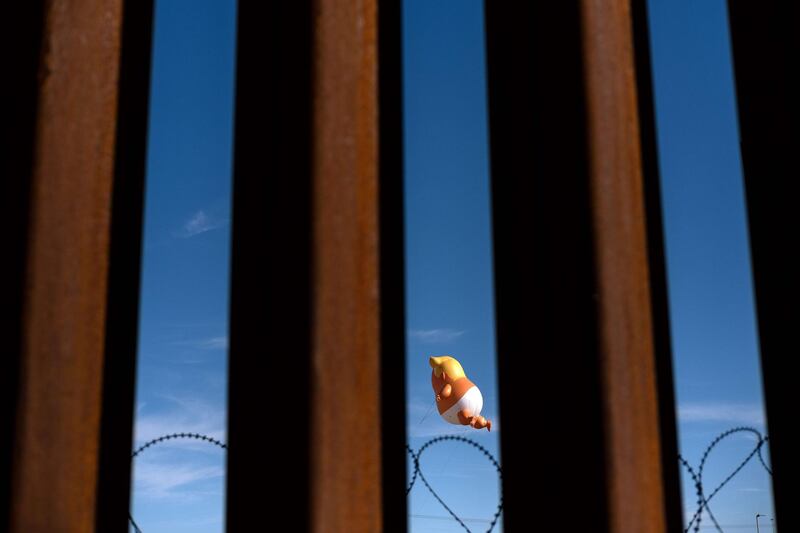 TOPSHOT - A satirical balloon of a baby US President Donald Trump is seen through the US-Mexico border fence during a demonstration against him prior to his visit to Calexico, California, as seen from Mexicali, Baja California state, Mexico, on April 5, 2019.  President Donald Trump flew Friday to visit newly built fencing on the Mexican border, even as he retreated from a threat to shut the frontier over what he says is an out-of-control influx of migrants and drugs. / AFP / Guillermo Arias
