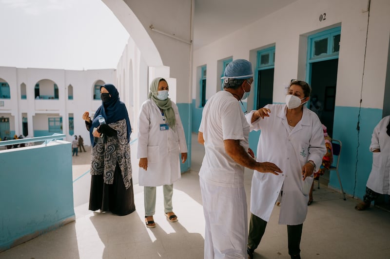 Doctors and nurses discuss another internet outtage as they wait for their patients at the vaccine centre in Mornag.