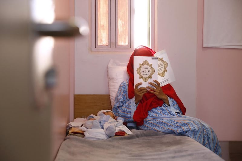 A mother reads the Quran while her baby sleeps.