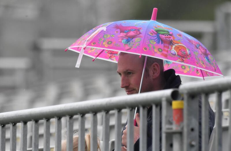 A fan shelters from the rain at Malahide. Clodagh Kilcoyne / Reuters