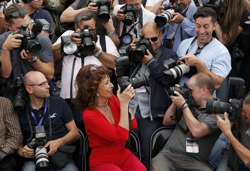 Actress Sophia Loren, centre, guest of honour, holds a camera as she sits with assembled photographers during a photocall for the film La Voce Umana presented as part of Cannes Classics at in competition at the 67th Cannes Film Festival in Cannes May 21, 2014. Regis Duvignau / Reuters  