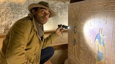 Ramy Romany looks at hieroglyphics with a flash light in Mummies Unwrapped. Courtesy Discovery
