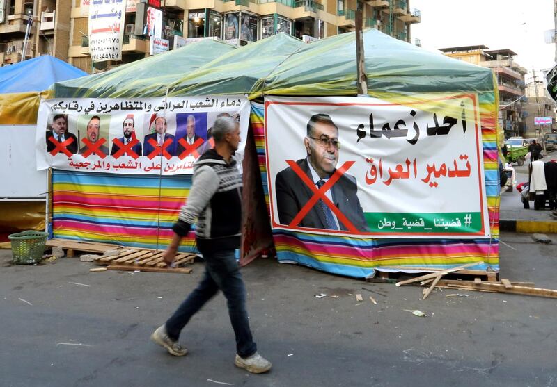 A protester walks by crossed pictures of senior Iraqi officials in Tahrir Square. EPA