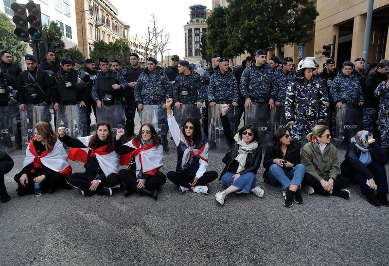 Anti-government protesters sit in the middle of a road to prevent the Lebanese MPs from reaching the parliament building to attend the 2020 budget discussion session. AP