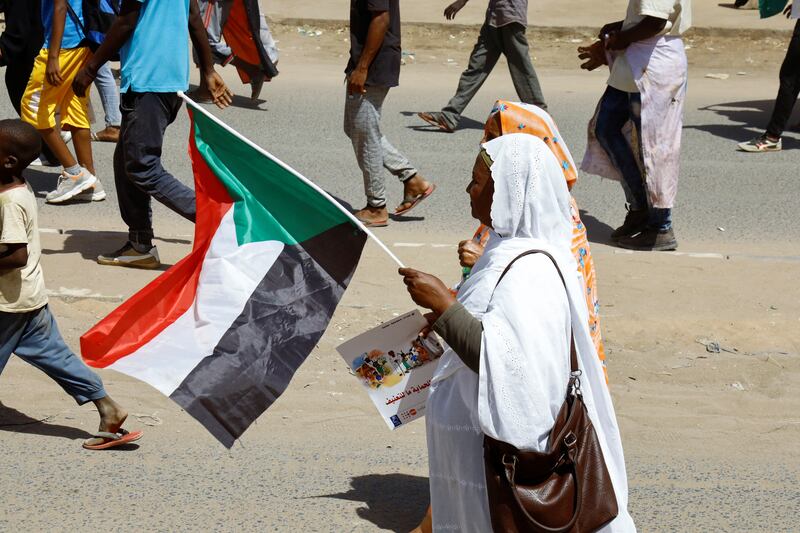A Sudanese woman carries a flag during the demonstration. Reuters
