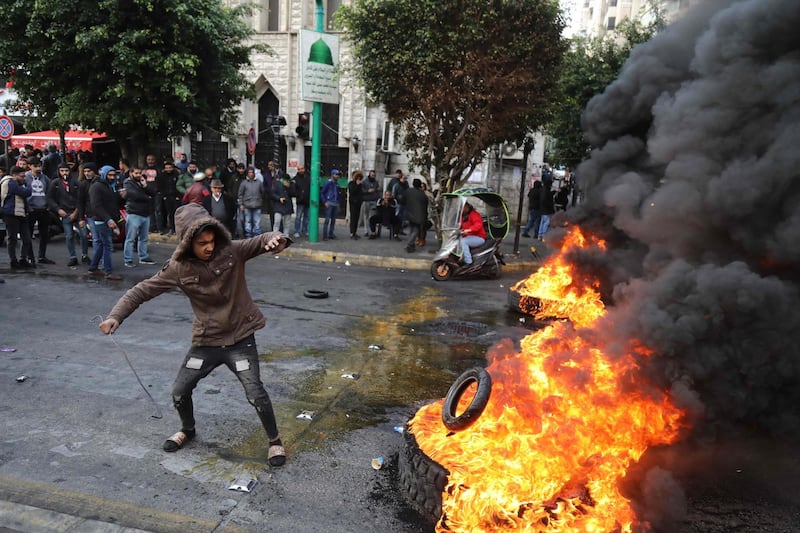 A protester throws a tyre on a burning pile blocking the road in the capital Beirut. AFP