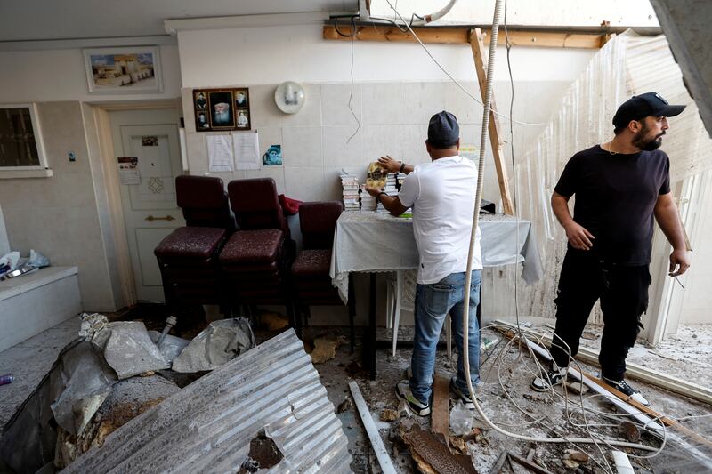 A man rearranges Jewish prayer books after a synagogue was hit by a rocket launched from the Gaza Strip into Ashkelon, southern Israel. Reuters