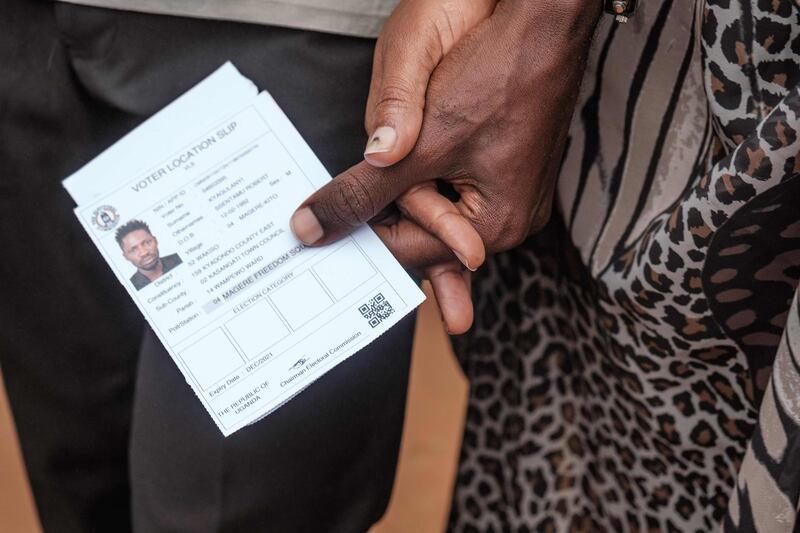 Bobi Wine holds his wife's Barbara Itungo Kyagulanyi hand, as well as his voter ID at a polling station in Magere, Uganda. AFP