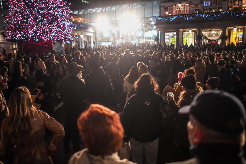 LONDON, ENGLAND  - DECEMBER 05:  Crowds of people listen to a busker in Covent Garden on December 5, 2020 in London, England. On Tuesday night, Dec 1, MPs voted in favour of government proposals to enter England into a tiered system of lockdown beginning at midnight. Residents of Tier Two - High Alert can socialise with anyone they live with or who is in their support bubble in any indoor setting, whether at home or in a public place. Outdoors they must observe the rule of six. Pubs and bars must close, unless operating as restaurants. Hospitality venues can only serve alcohol with substantial meals and must close between 11pm and 5am with last orders called at 10pm. Organised indoor sport, physical activity and exercise classes will be permitted if it is possible for people to avoid mixing with people they do not live with. Schools remain open. (Photo by Peter Summers/Getty Images)