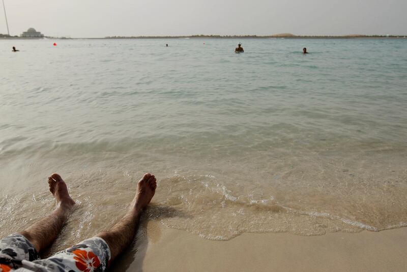 ABU DHABI, UNITED ARAB EMIRATES - April 27, 2009: A man cools off by siting in the water at the beach on the corniche, the weather was hot today as summer approaches in the United Arab Emirates. ( Ryan Carter / The National ) *** Local Caption ***  RC001-HotHot.JPGRC001-HotHot.JPG