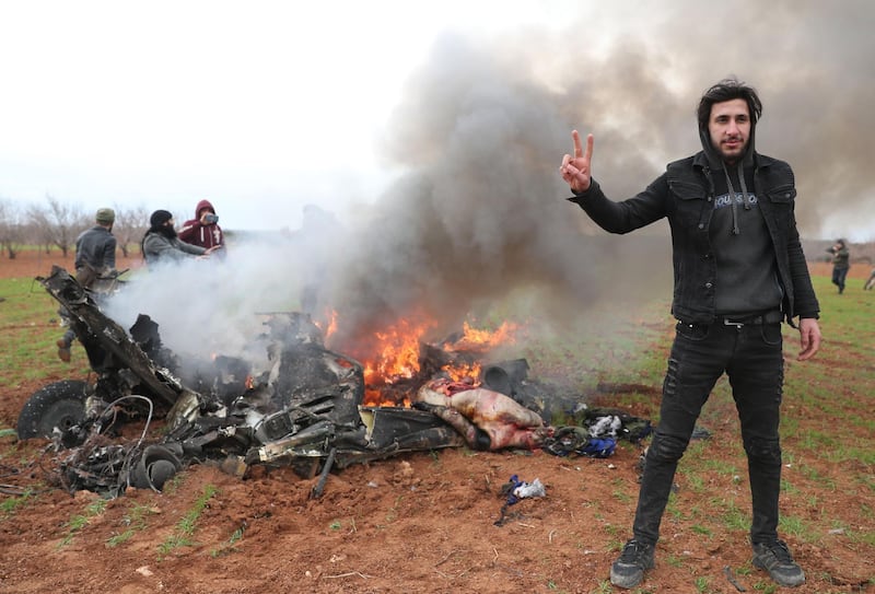 Syrian rebel fighters gather around the burning remains of a military helicopter after it was shot down over the village of Qaminas, about 6 kilometres southeast of Idlib city in northwestern Syria on February 11, 2020.  AFP