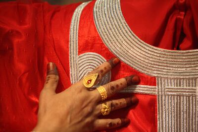 November 17, 2011, Abu Dhabi, UAE: Ateeja Ali Al Muhairbi holds up a Jalabiya that has used 'Talli' embroidery on the collar and cuffs.  Deepthi Unnikrishnan/The National *** Local Caption ***  DU1711_40@40Talli spindle_13.JPG