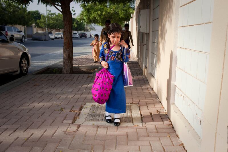 Sharjah, United Arab Emirates - June 23 2013 - Maitha Al Jabri, 4, (center) struggles to walk home as she carries two bags filled with sweets and crisps in the Leyyah district of the city. She has just participated in Hag El Leila, an Emirati tradition that occurs every year 15 days before the start of the month of Ramadan. The tradition involves children walking from door-to-door singing and collecting sweets and money. (Razan Alzayani / The National)  FOR RYM GHAZAL STORY   *** Local Caption ***  RA0623_hag_el_layla_014.jpg