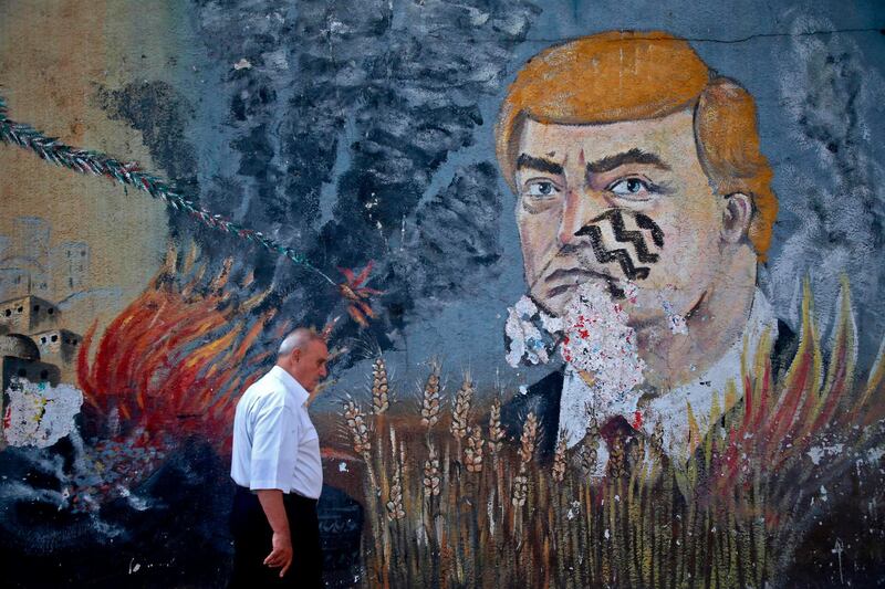 A Palestinian man walks past a mural depicting US President Donald Trump with a footprint on his face, on a street in the occupied Gaza City. AFP