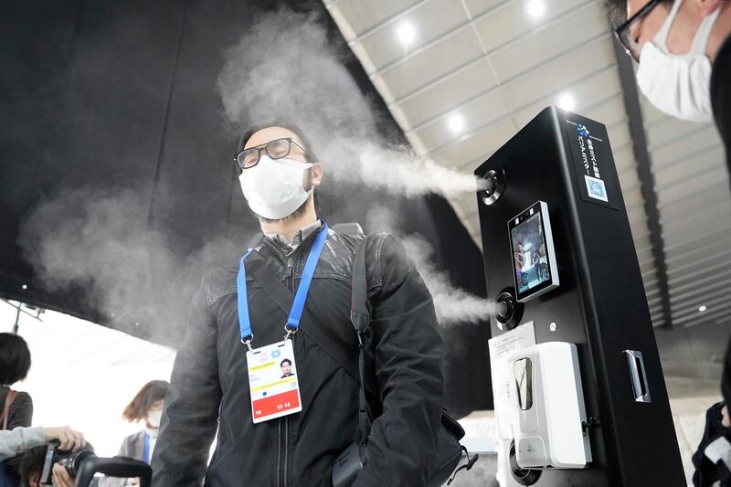 A member of the media is sprayed sterilization mist as he enters Yoyogi National Gymnasium in Yokyo. Getty