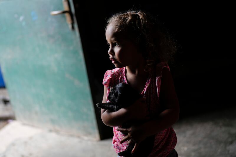 A girl cradles a puppy as her grandmother fills a container with water from a well in Caracas, Venezuela. World Water Day on March 22 coincides with the start of the UN Water Conference in New York. AP