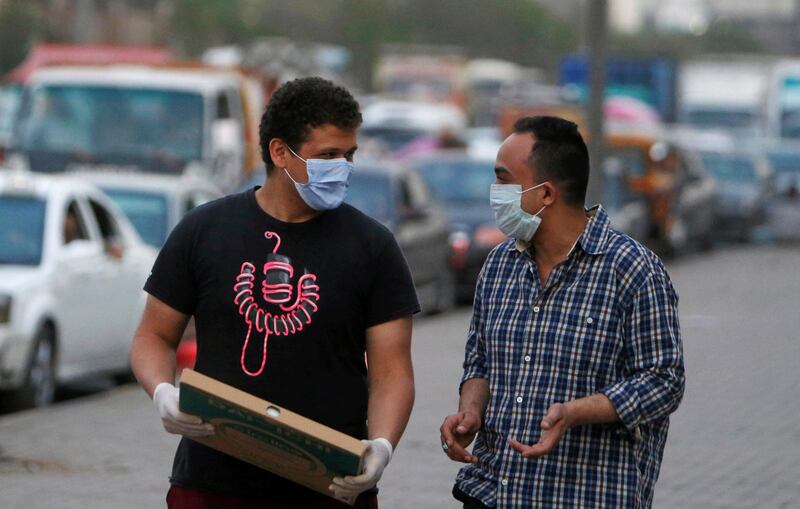Men wearing face masks walk along a street before curfew in Shubra El Kheima, Al Qalyubia Governorate, north of Cairo, Egypt. Reuters