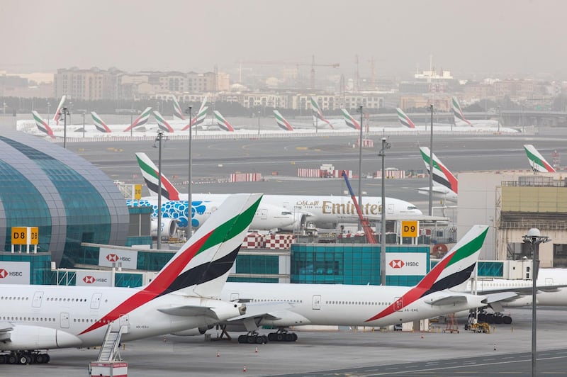 Passenger aircraft operated by Emirates stand beside the terminal building at Dubai International Airport.
