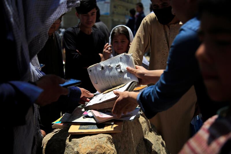 Afghans go through belongings left behind after deadly bombings on Saturday near a school in Kabul, Afghanistan, Sunday, May 9, 2021. The Interior Ministry said the death toll in the horrific bombing at the entrance to a girls' school in the Afghan capital has soared to some 50 people, many of them pupils between 11 and 15 years old, and the number of wounded in Saturday's attack has also climbed to more than 100. (AP Photo/Mariam Zuhaib)