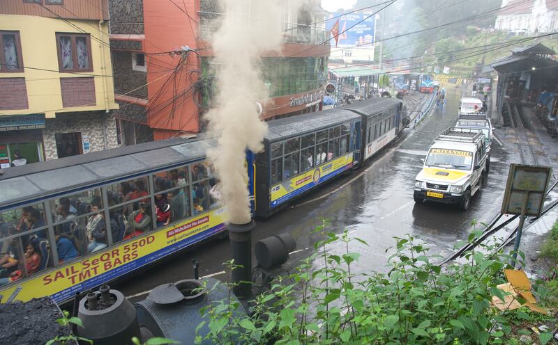 A steam engine alongside modern cars in Darjeeling