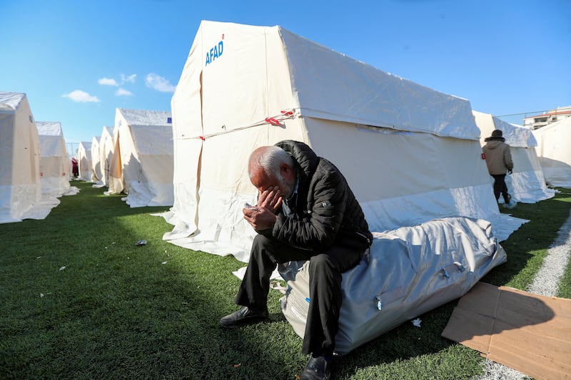 A man reacts while sitting outside a tent of a temporary accommodation centre set up on a football pitch in Gaziantep, Turkey. Reuters