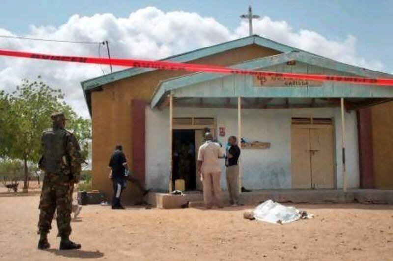 Members of the Kenyan security forces inspect the scene, as a body lies covered by a sheet, outside the African Inland Church in Garissa, Kenya.