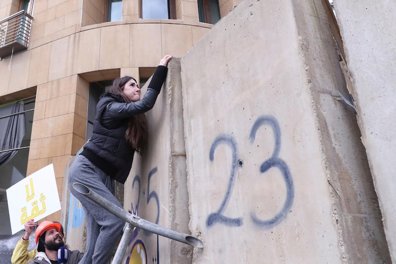 Lebanese journalist Dima Sadek climbs a wall installed by authorities to block a protest against a parliament session vote of confidence for the new government, in downtown Beirut, Lebanon. AP Photo