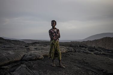 A local guide walks on the dry lava field of Erta Ale volcano, in the Danakil Depression of the Afar region, on March 23, 2024. - In the heart of the Horn of Africa, the Danakil Depression is one of the hottest, most inhospitable place on earth, with temperatures topping 50 degrees Celsius. With much of its territory lying an average of 100m below sea level, this scarcity populate area of the Afar region hosts one of only a handful of volcanoes to have an active lava lake, Erta Ale, and is littered with acid ponds, geysers and a deep crater with unearthly colours called Dallol. (Photo by Michele Spatari / AFP)