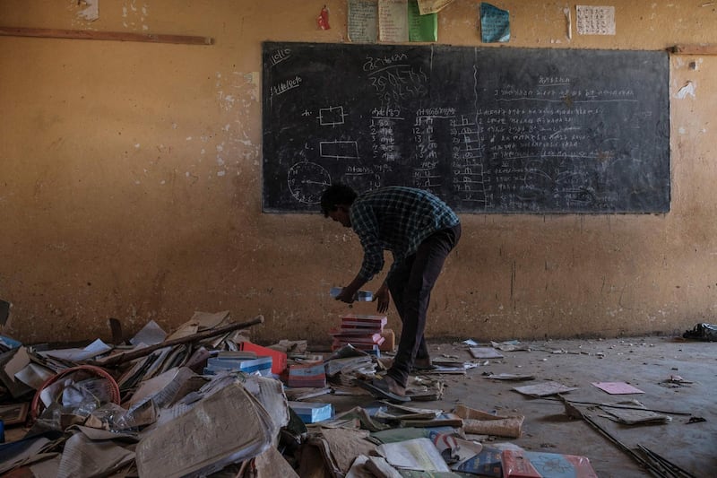 A youngster arranges books at a looted classroom at Ksanet Junior Secondary School, which was shelled as federal-aligned forces entered the city and looted allegedly by Eritrean forces, in Wukro, north of Mekele, on March 1, 2021. Every phase of the four-month-old conflict in Tigray has brought suffering to Wukro, a fast-growing transport hub once best-known for its religious and archaeological sites. 
Ahead of federal forces' arrival in late November 2020, heavy shelling levelled homes and businesses and sent plumes of dust and smoke rising above near-deserted streets. 
Since then the town has been heavily patrolled by soldiers, Eritreans at first, now mostly Ethiopians, whose abuses fuel a steady flow of civilian casualties and stoke anger with Nobel Peace Prize-winner Abiy. / AFP / EDUARDO SOTERAS
