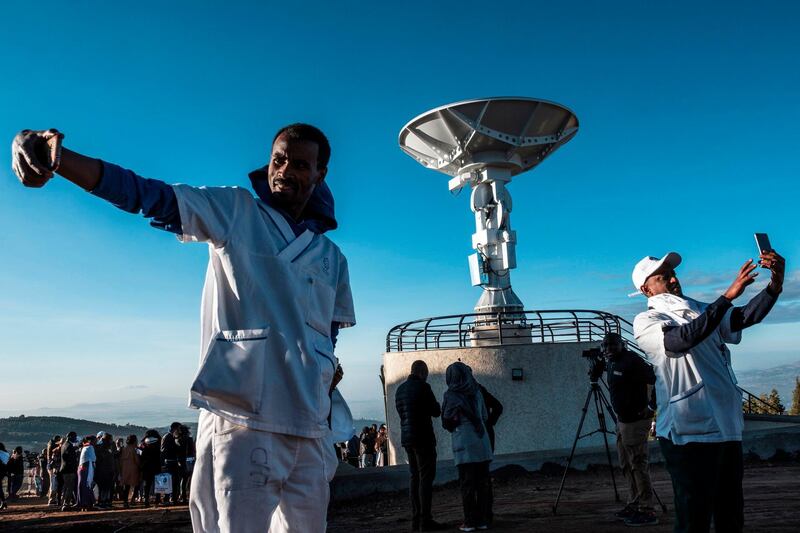 People take selfie pictures in front of a satellite antenna during the ceremony for the launching of the Ethiopian Remote Sensing Satellite (ETRSS) in Entoto Observatory and Research Centre in Addis Ababa, on December 20, 2019. Ethiopia launched its first satellite on December 20, 2019, a landmark achievement for the country's space programme that caps a banner year for the African space industry. The launch of the Ethiopian Remote Sensing Satellite (ETRSS) took place at a space station in China, though scores of Ethiopian and Chinese officials and scientists gathered at the Entoto Observatory and Research Centre outside the capital, Addis Ababa, early Friday to watch a live broadcast / AFP / EDUARDO SOTERAS
