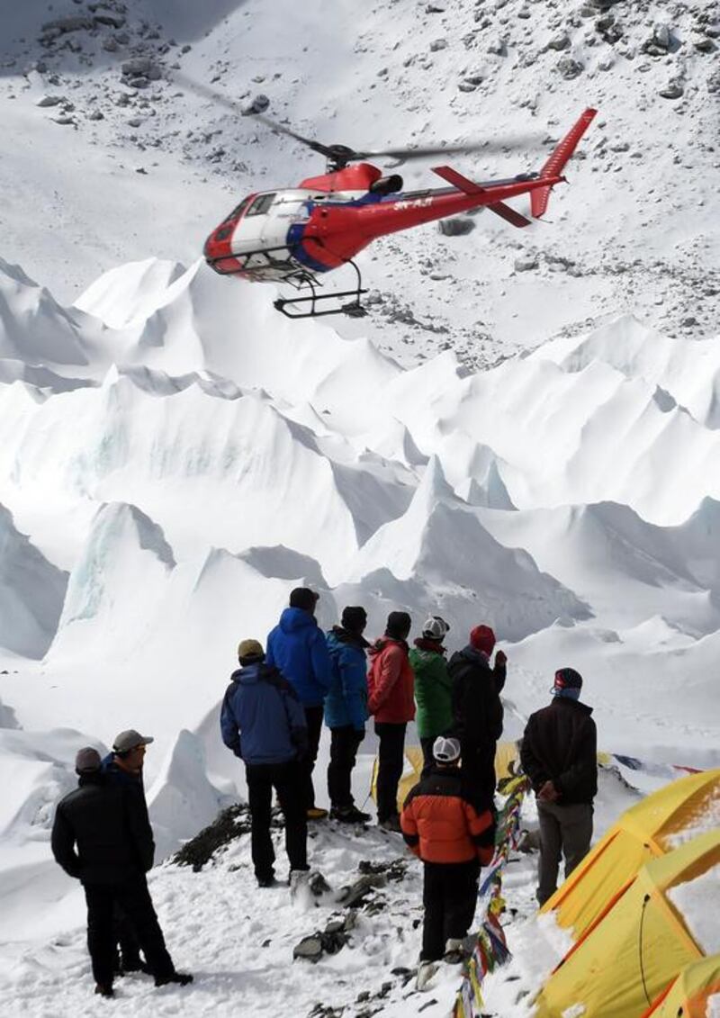 Nepali sherpas and other Nepali members of expeditons watch as a rescue helicopter takes off.