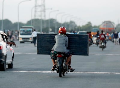epa08912539 A woman holds a solar panel as she rides on the back of the motorbike in Yangon, Myanmar, 31 December 2020.  EPA/NYEIN CHAN NAING