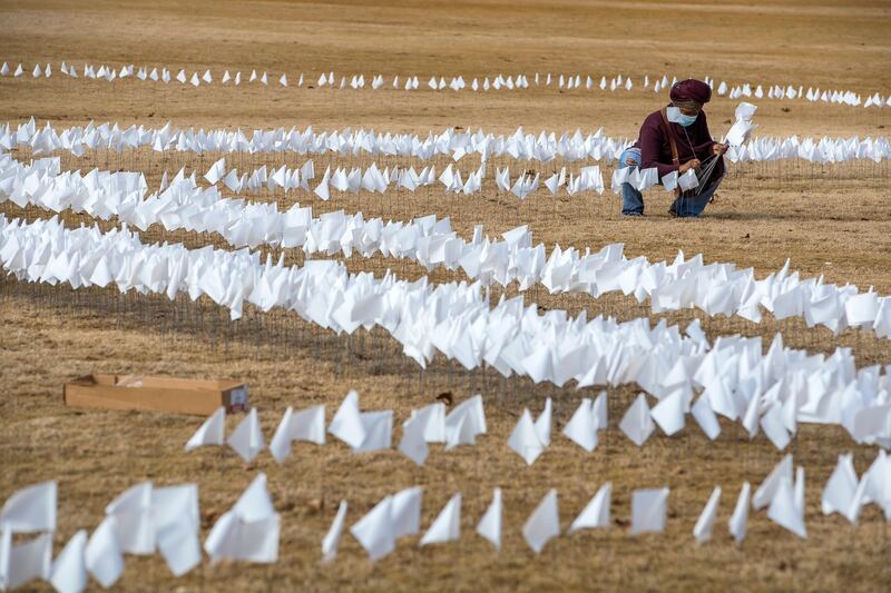 Tanya Washington helps place some of the more than 10,000 white flags representing Covid-19 related deaths in the state of Georgia, at Piedmont Park in Atlanta, Georgia. EPA