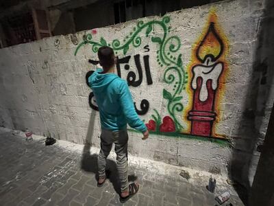 Calligrapher Abdullah Herz, 24, writes on a wall in Gaza city. Nagham Mohanna for The National