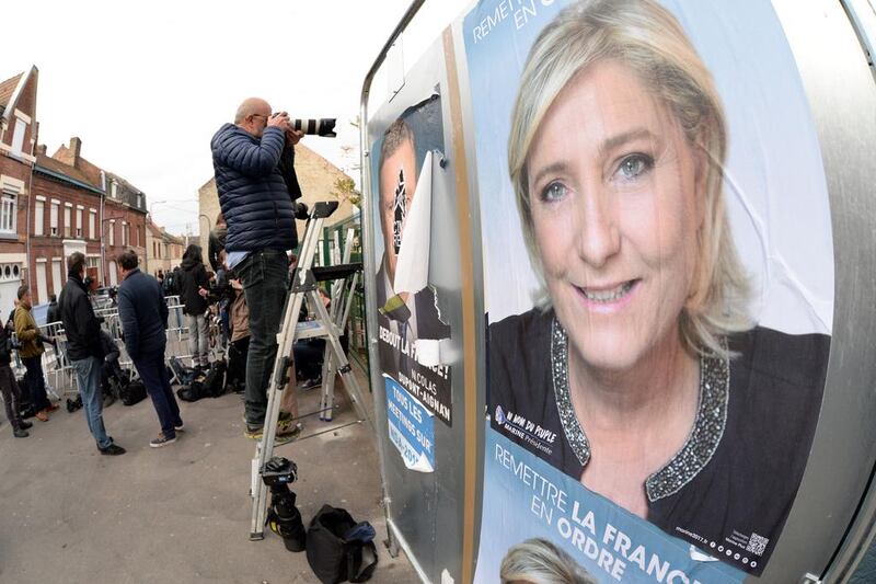 Photographers and journalists stand next to a campaign poster of French presidential election candidate for the far-right Front National party Marine Le Pen outside a polling station in Henin-Beaumont, northern France. Francois Lo Presti/AFP