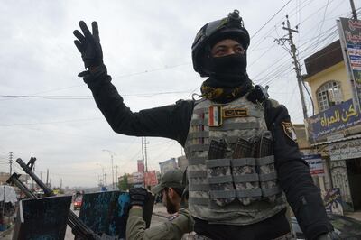 A member of the Iraqi security forces salutes onlookers as he parades in the streets of the Iraqi city of Mosul, during celebrations marking the first anniversary of the country's victory over the Islamic State (IS) group, on December 10, 2018.  A year since Iraq announced "victory" over the Islamic State group, the country finds itself in the throes of political and economic crises left unresolved during the long battle against jihadists. / AFP / Zaid AL-OBEIDI
