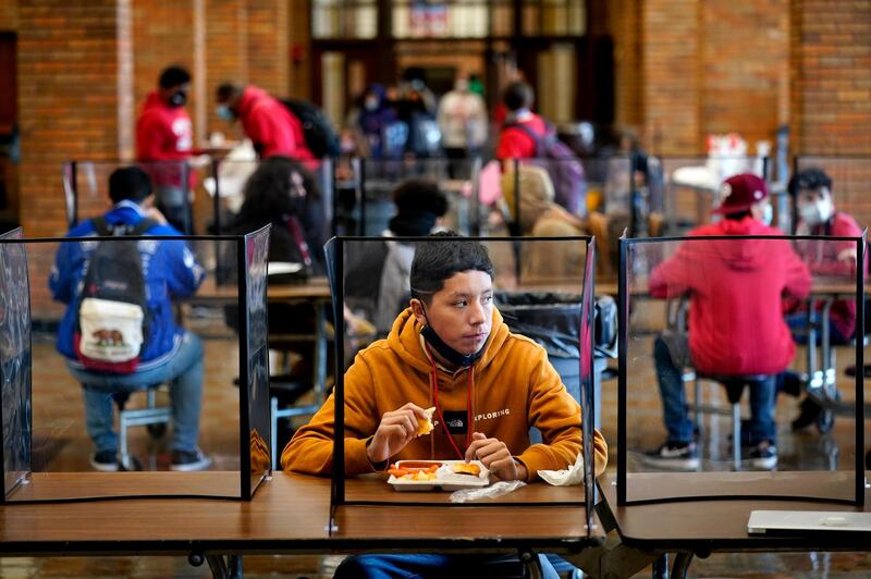 FILE - In this March 31, 2021, file photo, freshman Hugo Bautista eats lunch separated from classmates by plastic dividers at Wyandotte County High School in Kansas City, Kan., on the first day of in-person learning. With a massive infusion of federal aid coming their way, schools across the U.S. are weighing how to use the windfall to ease the harm of the pandemic â€” and to tackle problems that existed long before the coronavirus. (AP Photo/Charlie Riedel, File)