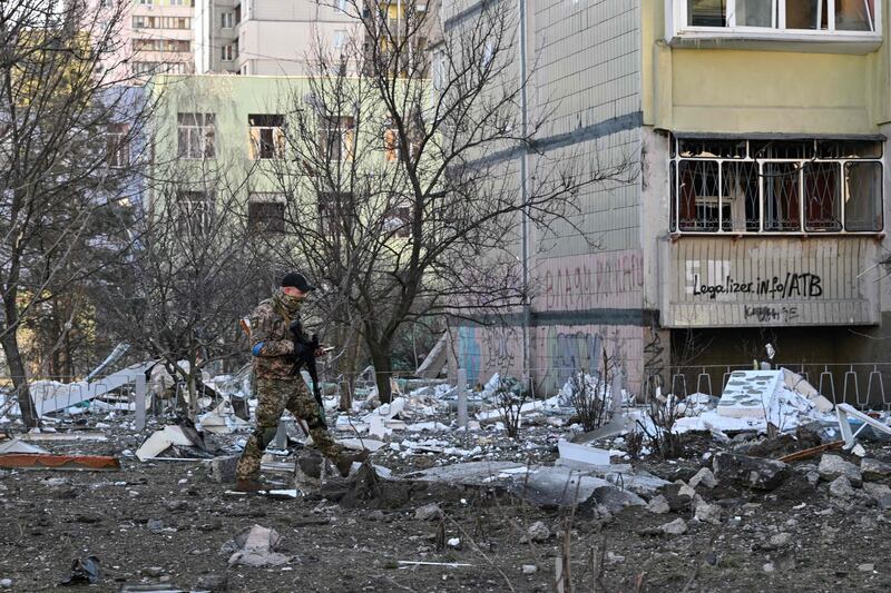 A member of Ukraine's defence forces walks by a damaged apartment block in Kyiv. AFP